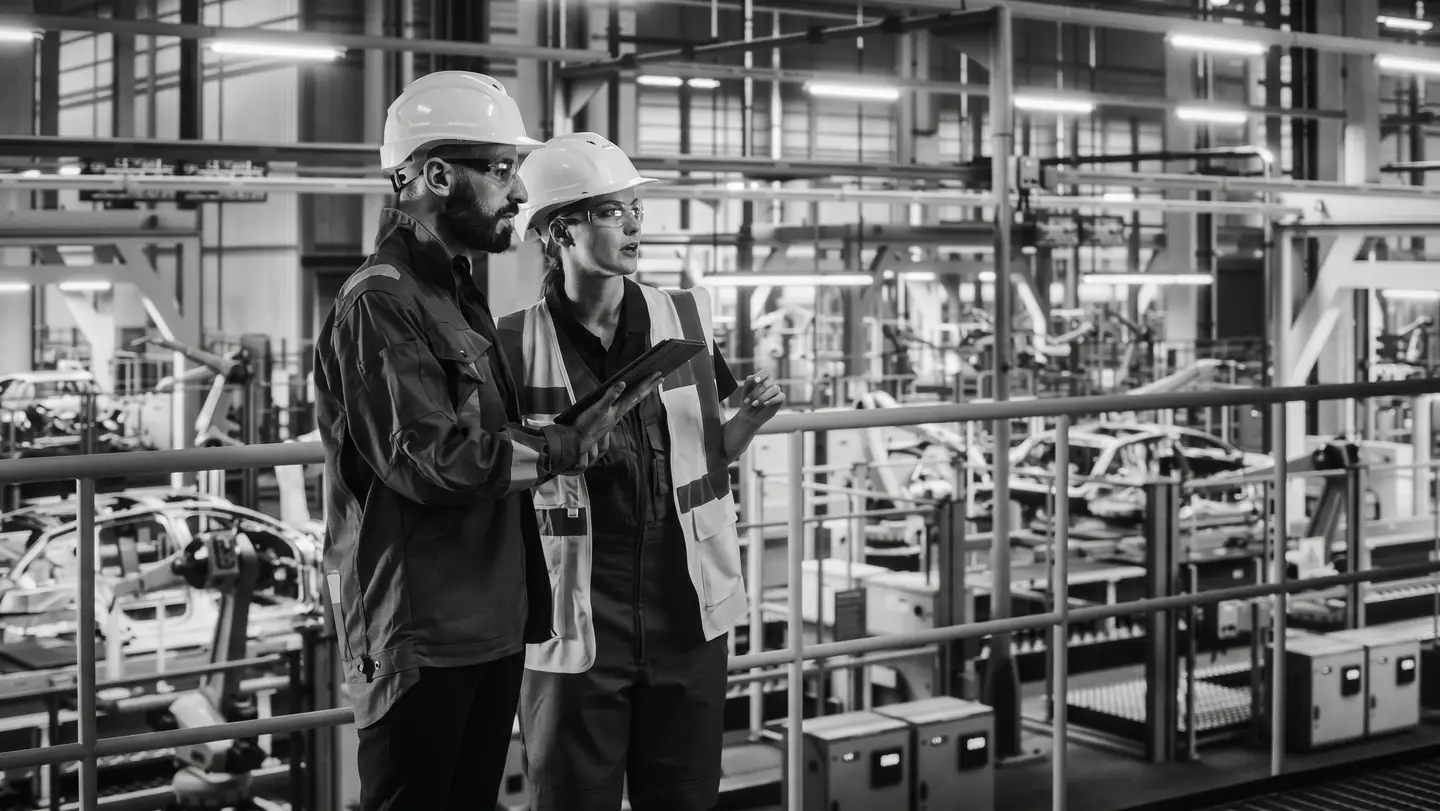 Dos personas con casco recorriendo una planta industrial